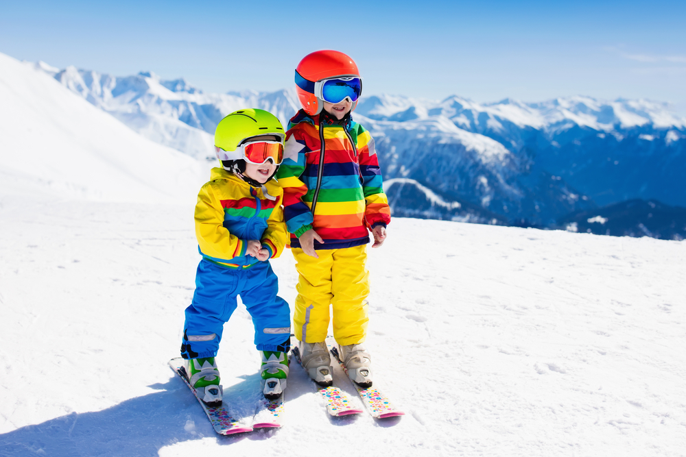 Dve deti sa učia lyžovať na lyžiarskom svahu.